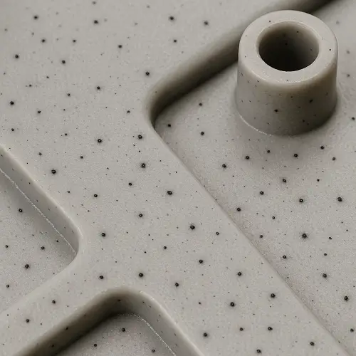 Fine black specks distributed across a molded plastic part, typically caused by degraded resin or contamination in the melt stream.