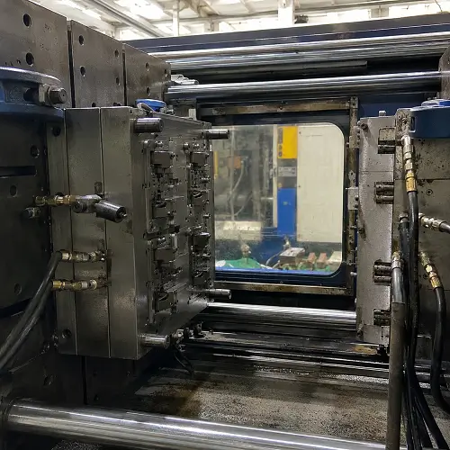 Injection molding machine with a mounted steel mold inside a real factory production setting.